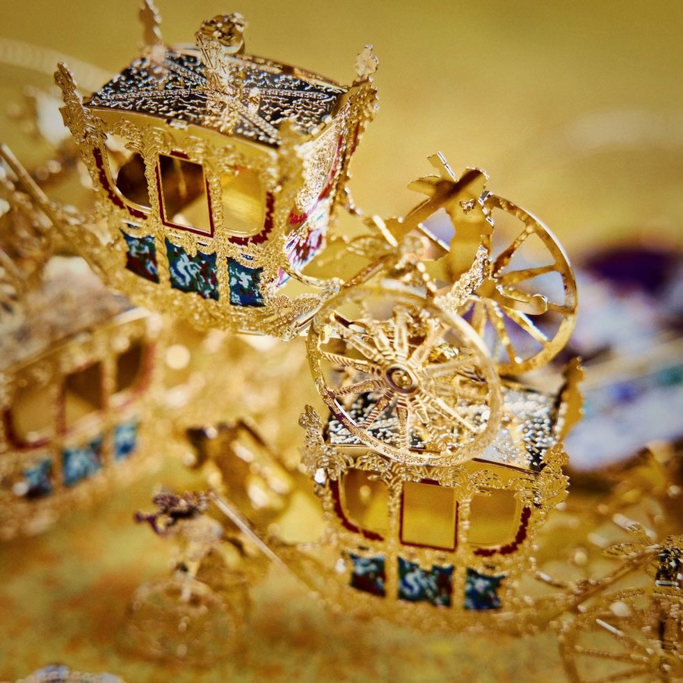 Handcrafted Gold State Coach Christmas Tree Ornament, featuring intricate 24-carat gold details. A stunning royal carriage replica by The London Christmas Company, perfect for adding British elegance to your festive decor. Seen here stacked in a pile of three.