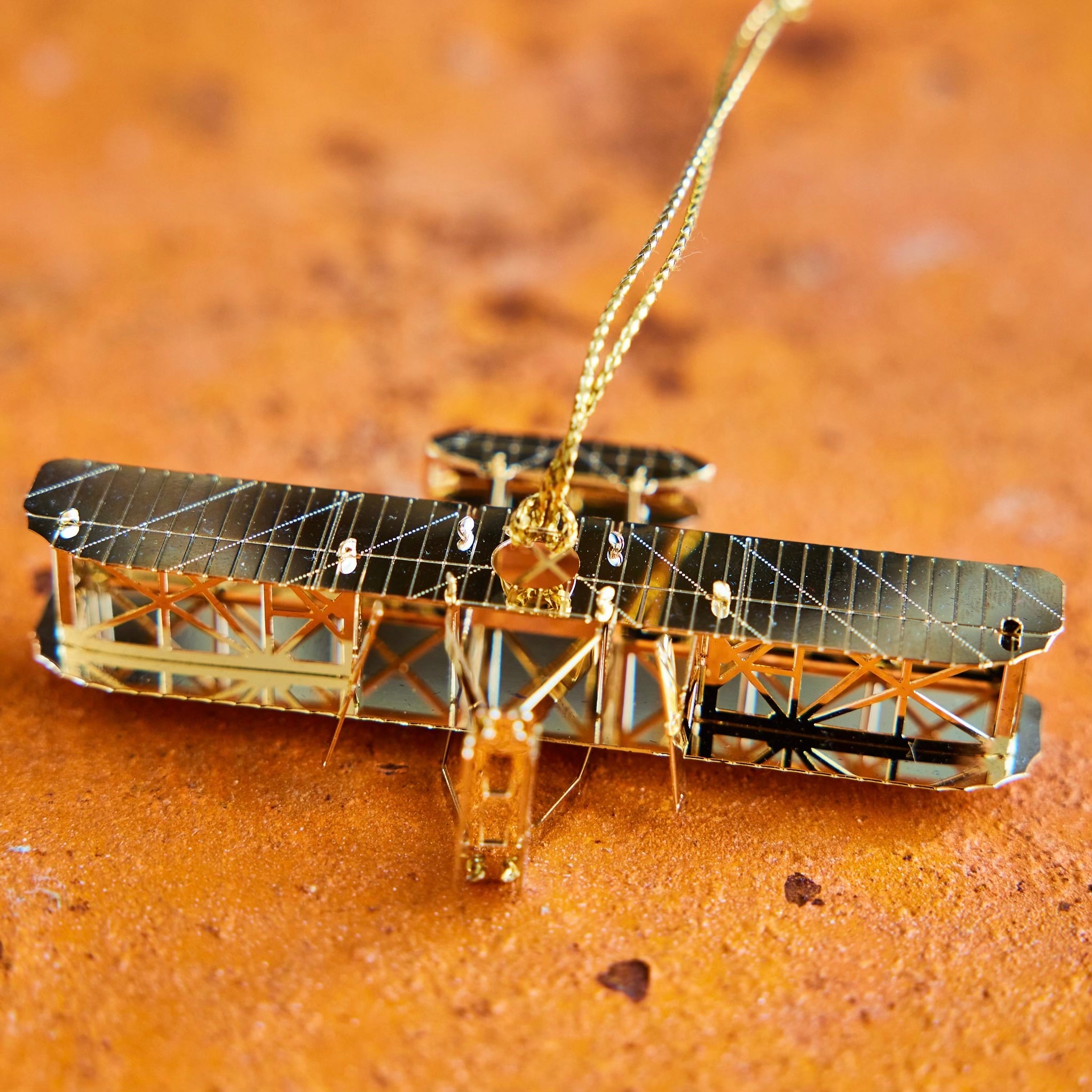 Handcrafted 24-carat gold finished Wright Brothers Flyer Christmas Tree Ornament by The London Christmas Company, celebrating the iconic first powered flight. A unique aviation-themed ornament perfect for adding history and elegance to your holiday decor. Seen here laying.