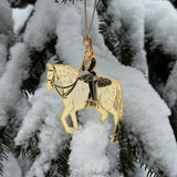 British Military Blues & Royals Christmas Ornament featuring a gold-finished, brass mounted horse and soldier in traditional uniform. Hanging in snowy tree. A luxurious holiday decoration inspired by the historic British regiment.