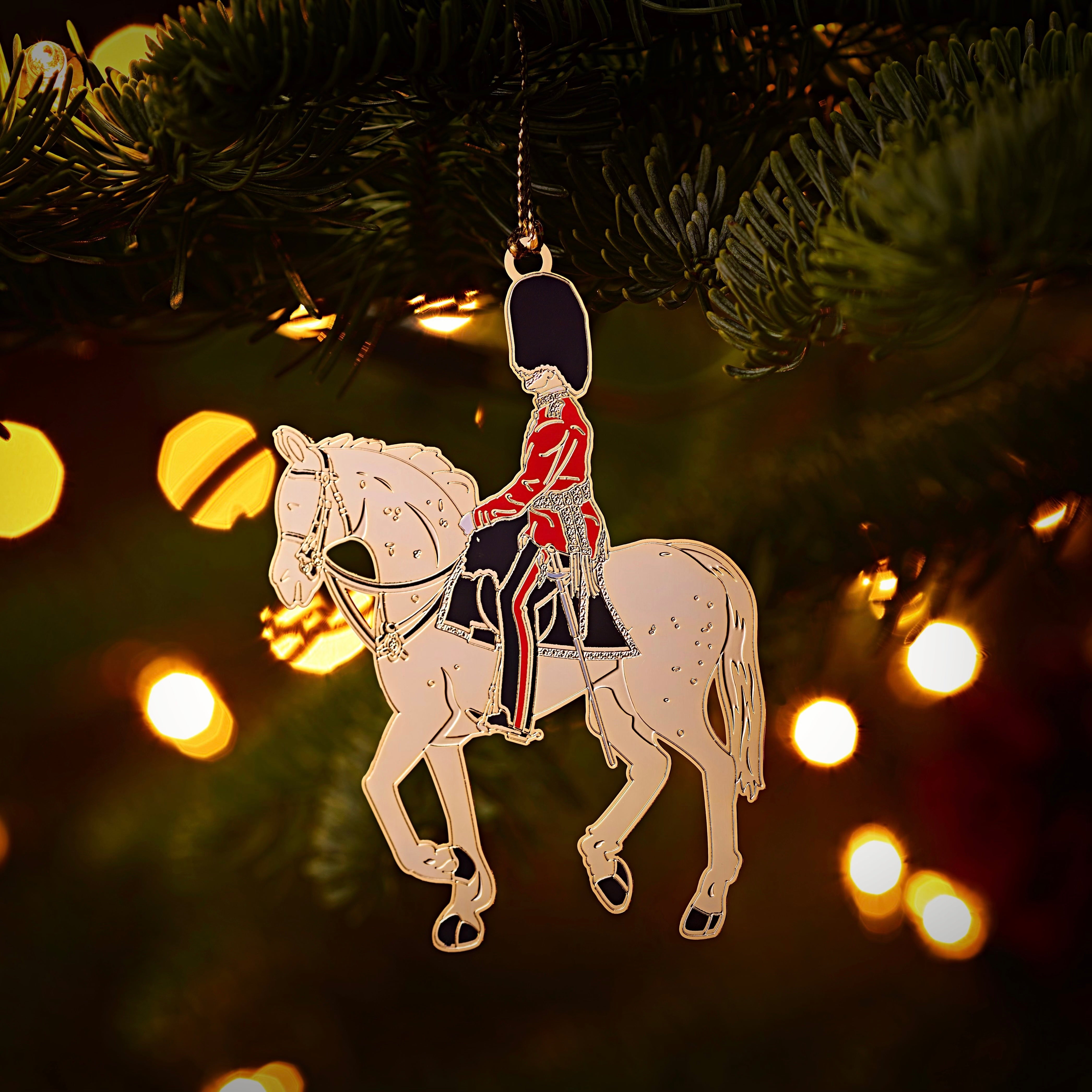 British Military Coldstream Guard Christmas Ornament Hanging in a Christmas Tree featuring a gold-finished, brass mounted horse and soldier in traditional uniform. A luxurious holiday decoration inspired by the historic British regiment.