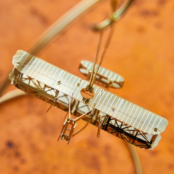 Handcrafted 24-carat gold finished Wright Brothers Flyer Christmas Tree Ornament by The London Christmas Company, celebrating the iconic first powered flight. A unique aviation-themed ornament perfect for adding history and elegance to your holiday decor. Seen here hanging.